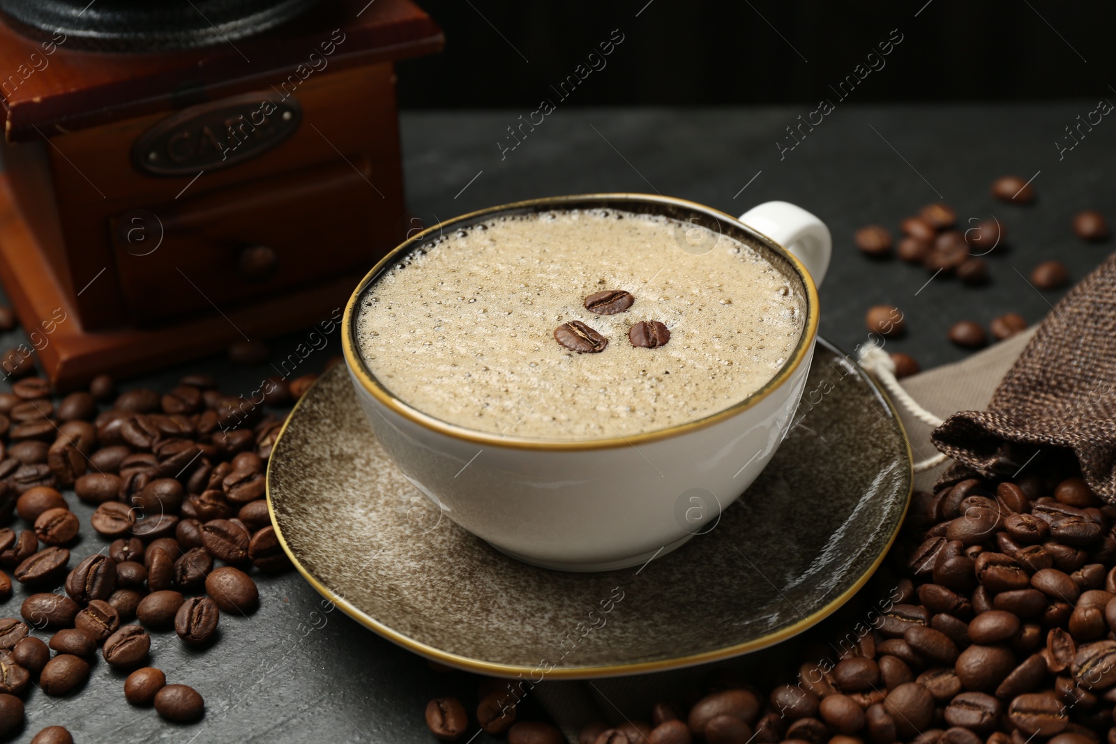 Aromatic coffee in cup, beans and grinder on black table, closeup Photo of Aromatic coffee in cup, beans and grinder on black table, closeup