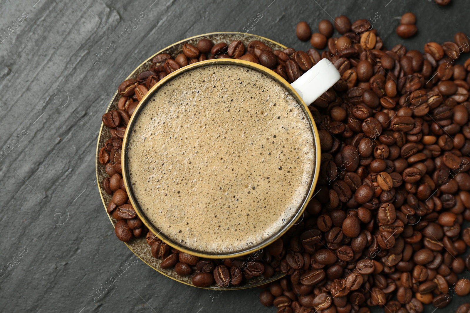 Aromatic coffee in cup and beans on black table, flat lay Photo of Aromatic coffee in cup and beans on black table, flat lay