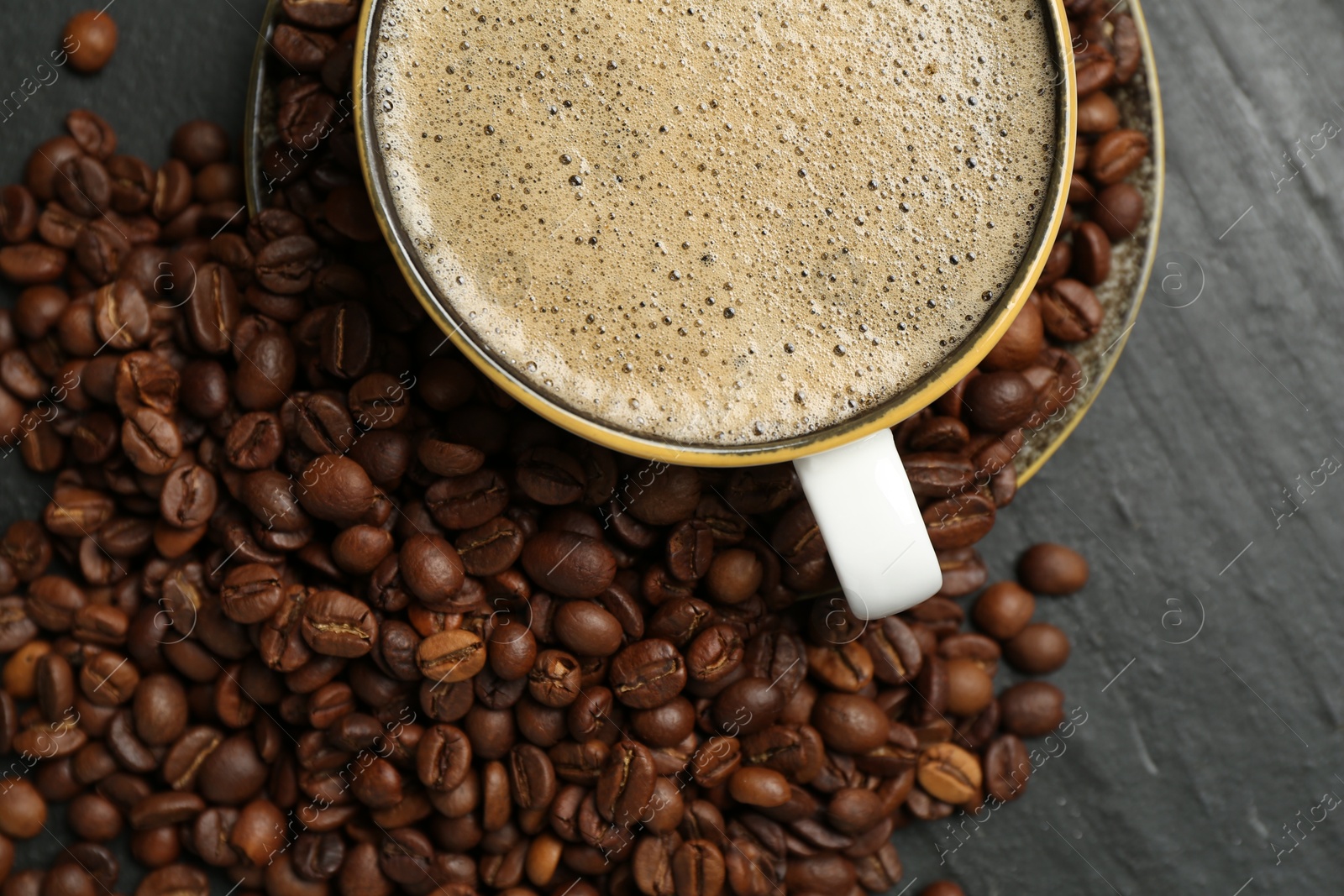 Aromatic coffee in cup and beans on black table, flat lay Photo of Aromatic coffee in cup and beans on black table, flat lay