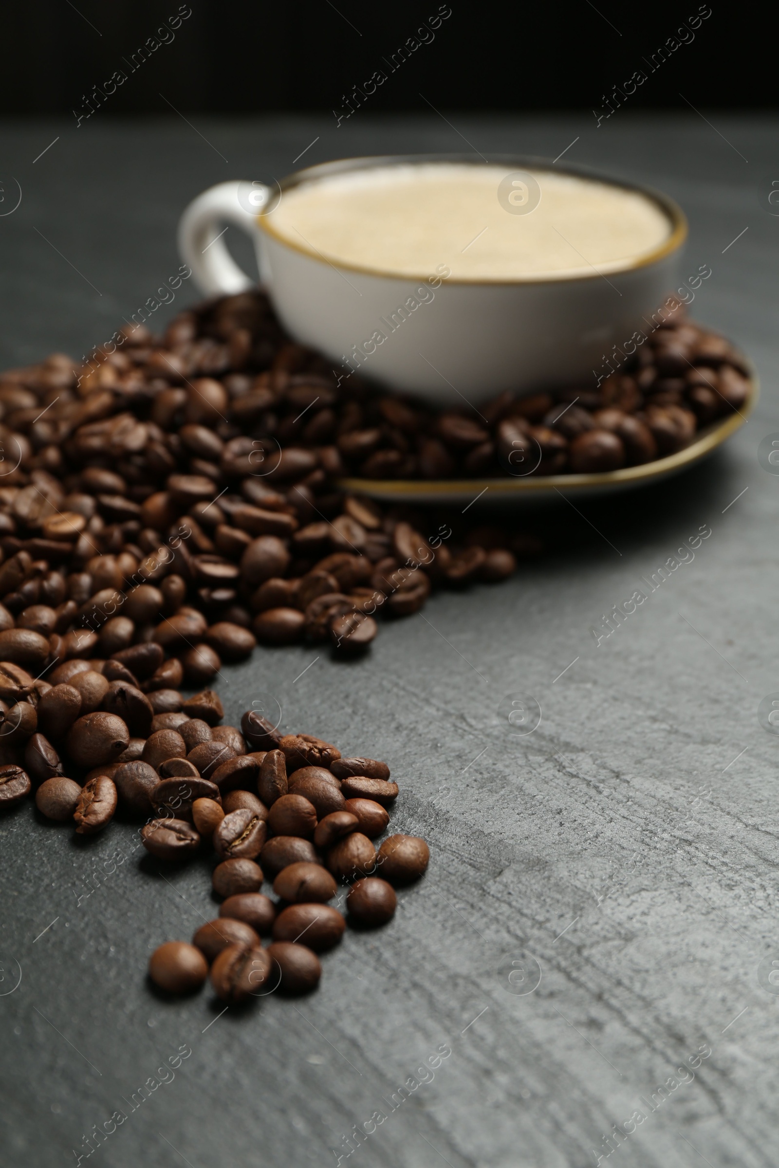 Aromatic coffee in cup and beans on black table, closeup Photo of Aromatic coffee in cup and beans on black table, closeup