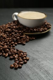Photo of Aromatic coffee in cup and beans on black table, closeup