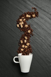 Photo of Aromatic coffee beans, brown sugar and cup on black table, flat lay