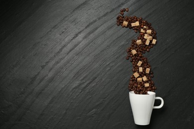 Photo of Aromatic coffee beans, brown sugar and cup on black table, flat lay. Space for text