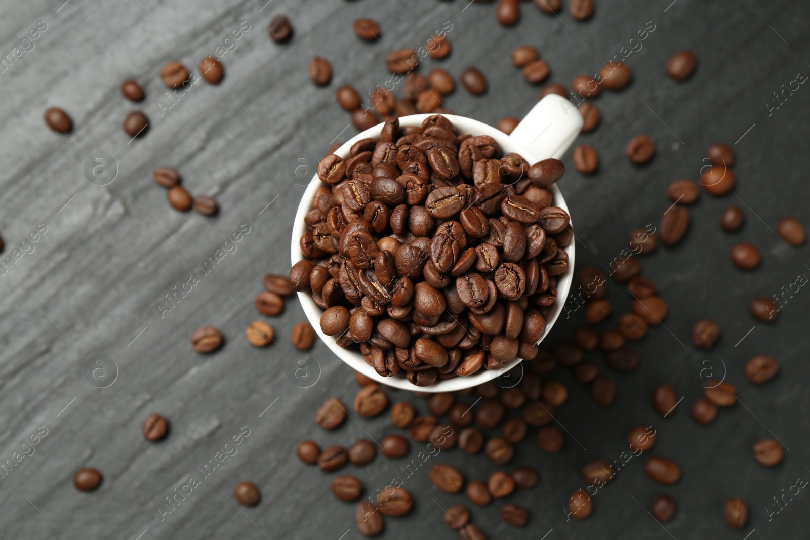 Aromatic coffee beans in cup on black table, flat lay Photo of Aromatic coffee beans in cup on black table, flat lay