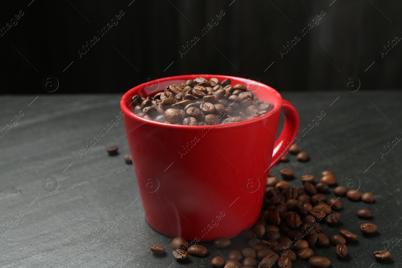 Aromatic coffee beans in cup on black table, closeup Photo of Aromatic coffee beans in cup on black table, closeup