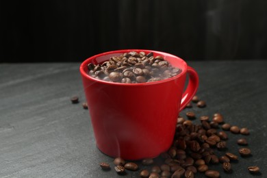 Photo of Aromatic coffee beans in cup on black table, closeup