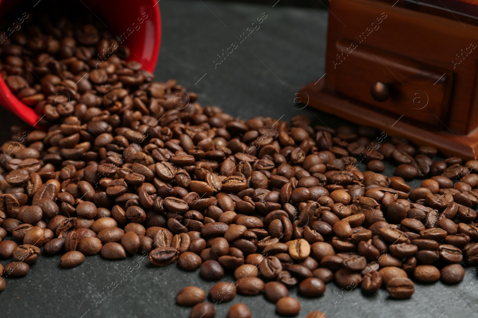 Aromatic coffee beans and grinder on black table, closeup Photo of Aromatic coffee beans and grinder on black table, closeup