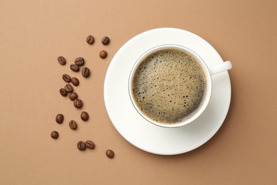 Photo of Aromatic coffee in cup and beans on beige background, flat lay