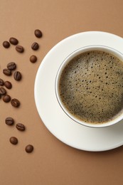 Photo of Aromatic coffee in cup and beans on beige background, flat lay