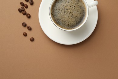 Photo of Aromatic coffee in cup and beans on beige background, flat lay. Space for text