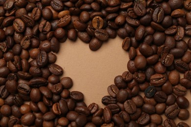 Photo of Heart shaped of coffee beans on beige background, flat lay