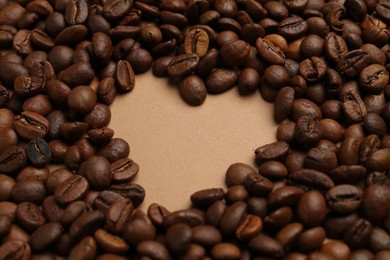 Photo of Heart shaped of coffee beans on beige background, closeup