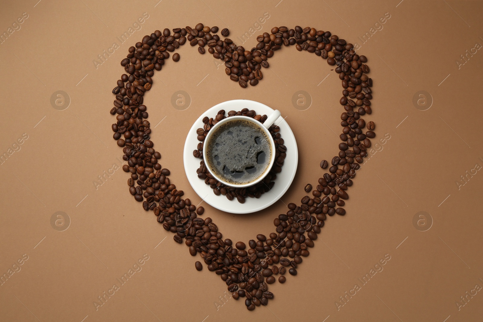 Aromatic coffee in cup and heart shaped of beans on beige background, flat lay Photo of Aromatic coffee in cup and heart shaped of beans on beige background, flat lay