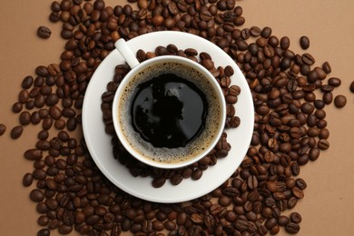 Photo of Aromatic coffee in cup and beans on beige background, flat lay