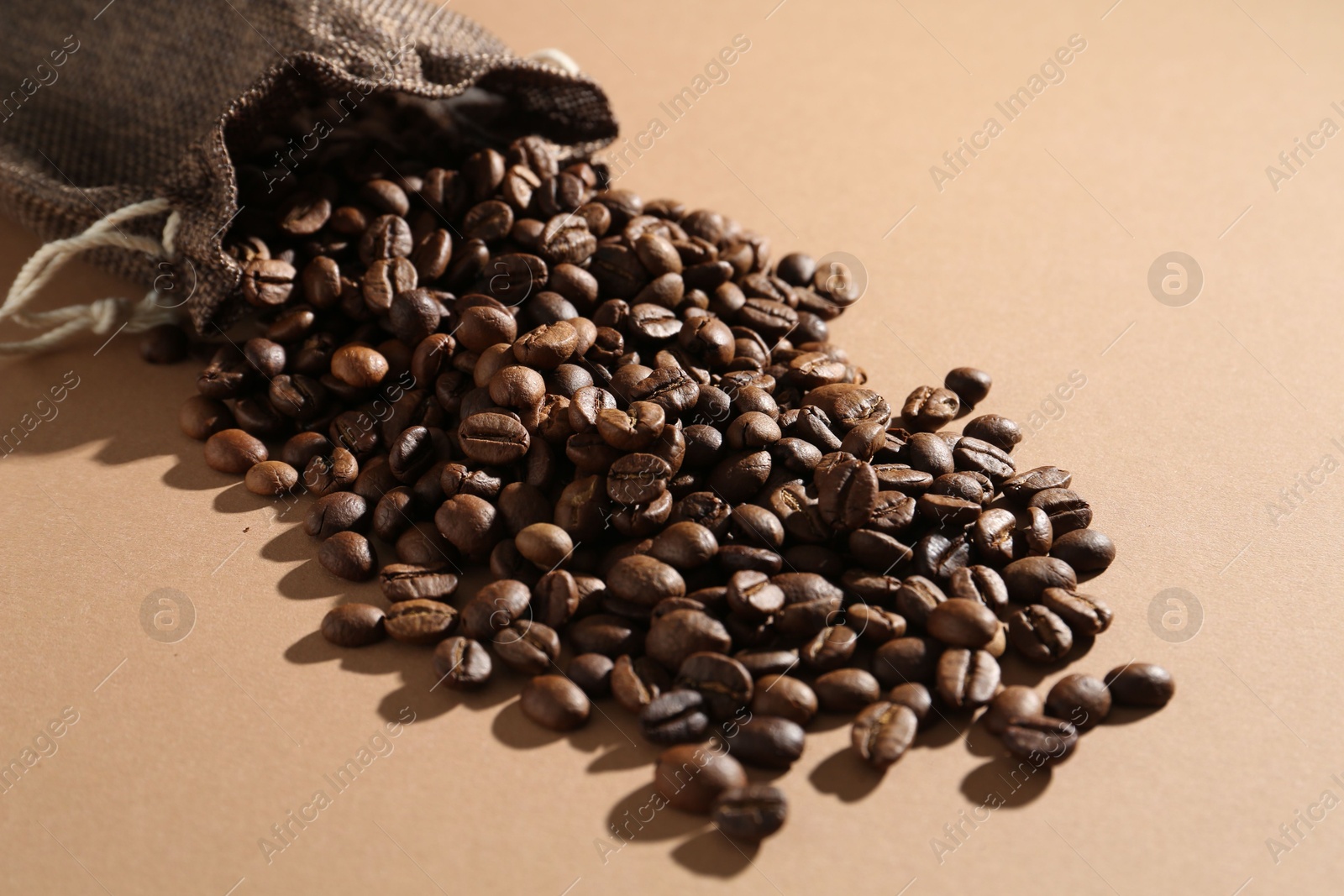 Aromatic coffee beans and sack on beige background, closeup Photo of Aromatic coffee beans and sack on beige background, closeup
