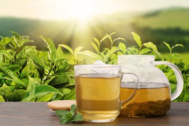 Image of Green tea in cup and teapot on wooden table in tea plantation