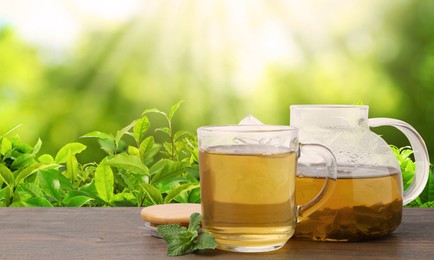 Image of Green tea in cup and teapot on wooden table in tea plantation. Banner design with space for text
