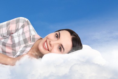 Image of Young woman lying on fluffy cloud in blue sky. Bedtime