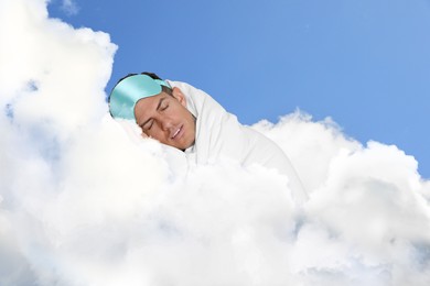 Image of Man with blanket and mask sleeping on fluffy cloud in blue sky. Bedtime