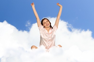 Image of Young woman stretching on fluffy cloud in blue sky