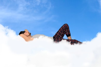 Image of Man sleeping on fluffy cloud in blue sky. Bedtime