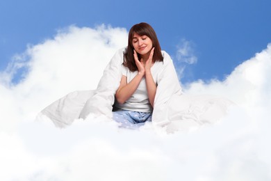 Image of Woman with blanket on fluffy cloud in blue sky. Bedtime