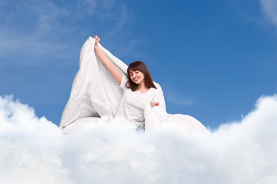 Image of Happy woman with blanket on fluffy cloud in blue sky. Bedtime