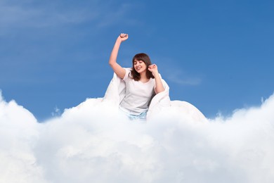 Image of Happy woman with blanket stretching on fluffy cloud in blue sky