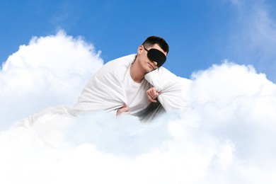 Image of Man with blanket and sleep mask on fluffy cloud in blue sky. Bedtime
