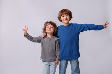 Photo of Cute little brothers showing V-signs on white background