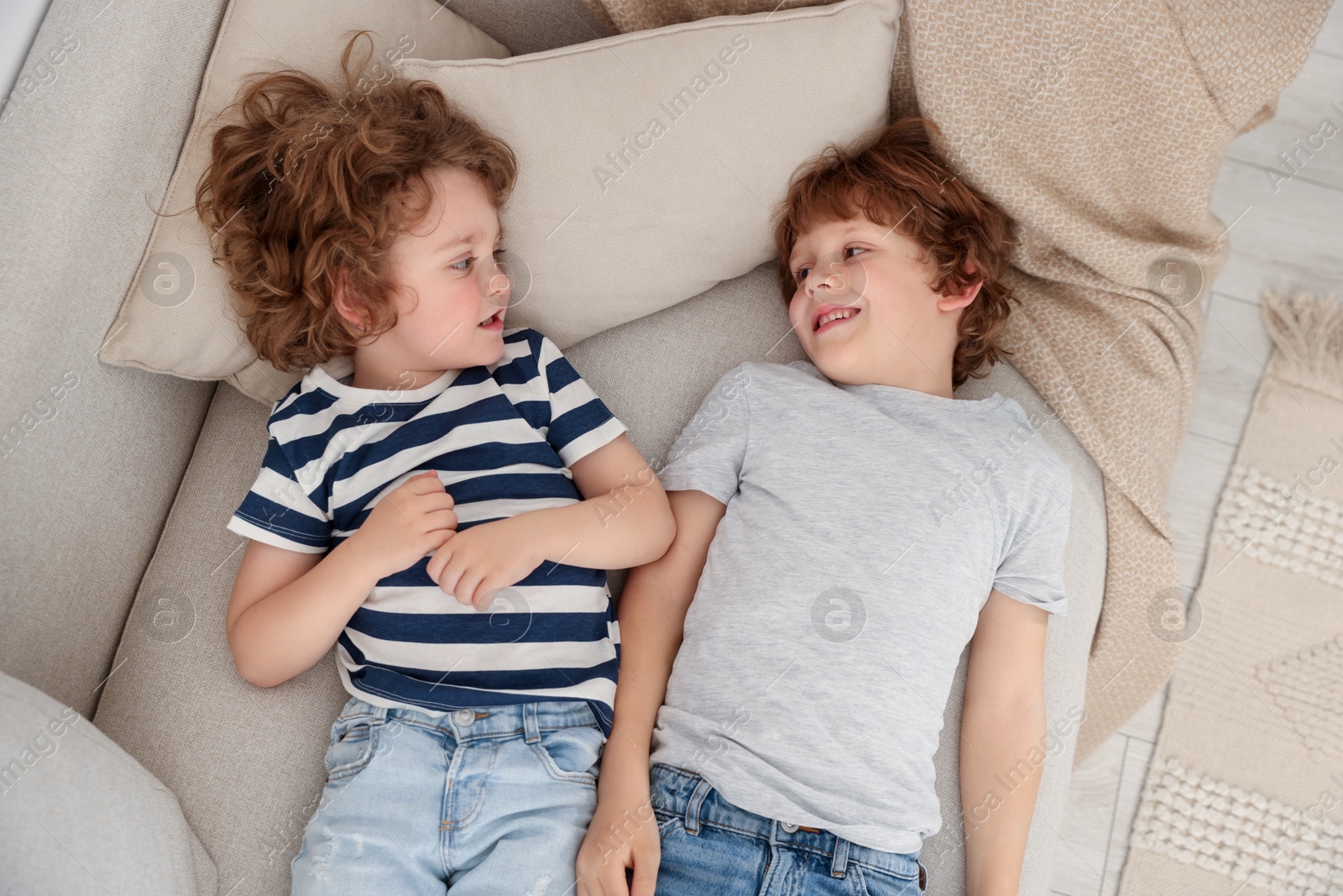 Cute little brothers laying together on sofa, above view Photo of Cute little brothers laying together on sofa, above view