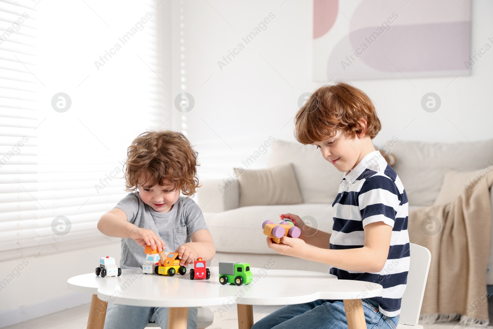 Cute little brothers playing with toys at table indoors Photo of Cute little brothers playing with toys at table indoors