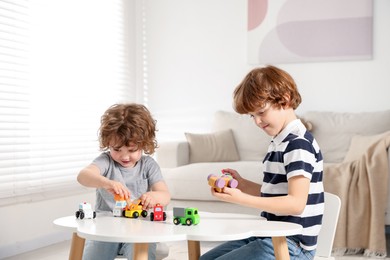 Photo of Cute little brothers playing with toys at table indoors