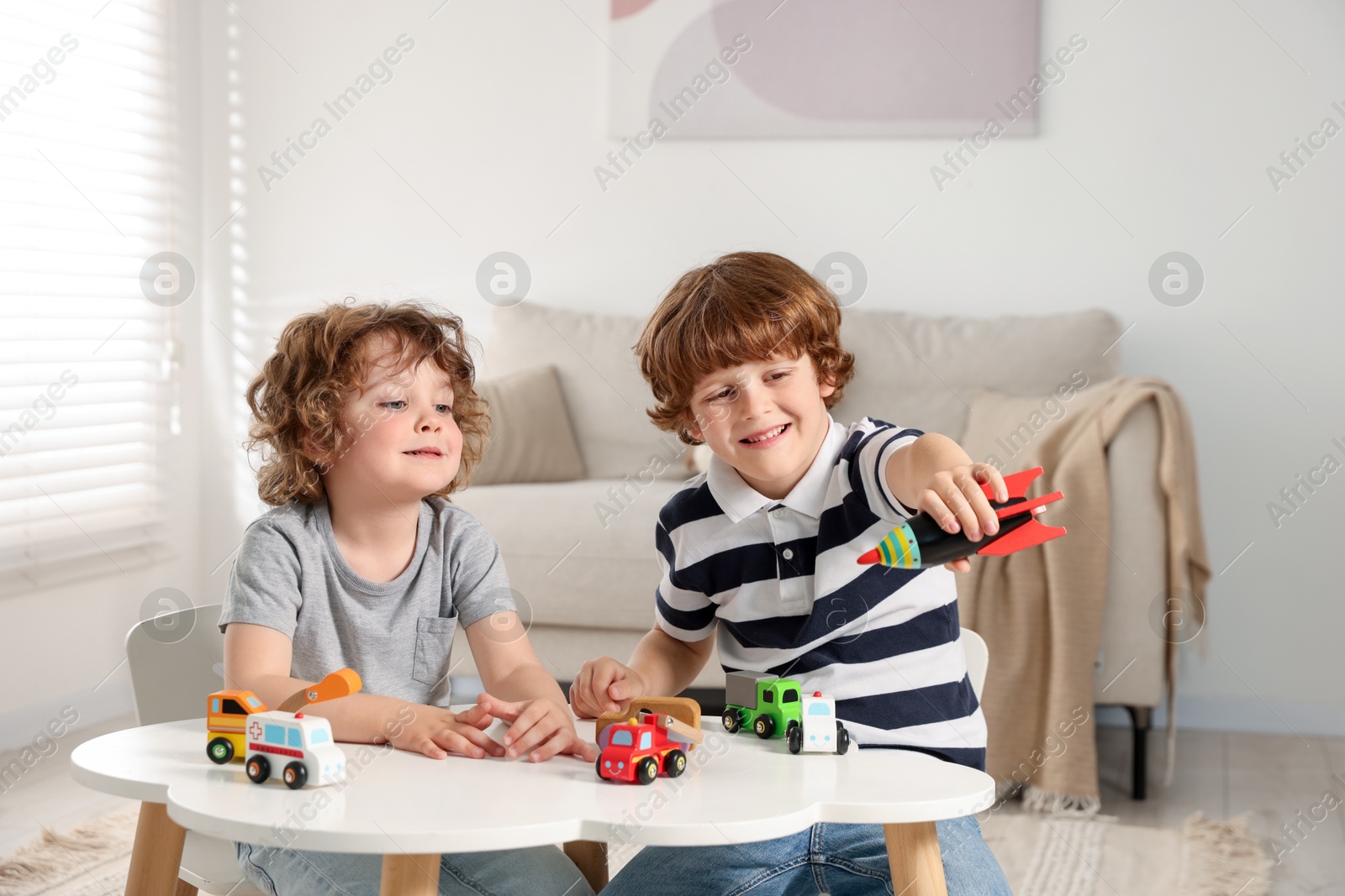 Cute little brothers playing with toys at table indoors Photo of Cute little brothers playing with toys at table indoors