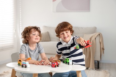 Photo of Cute little brothers playing with toys at table indoors