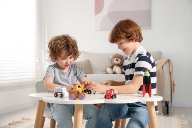 Photo of Cute little brothers playing with toys at table indoors