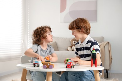 Photo of Cute little brothers playing with toys at table indoors