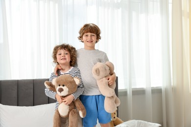 Photo of Cute little brothers with toys on bed at home