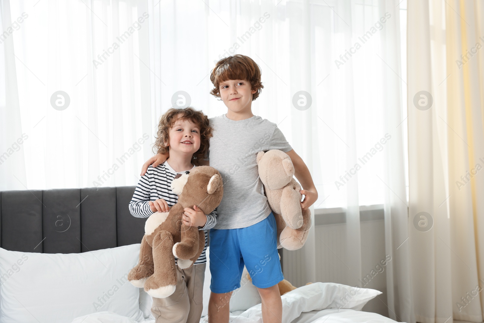 Cute little brothers with toys on bed at home Photo of Cute little brothers with toys on bed at home