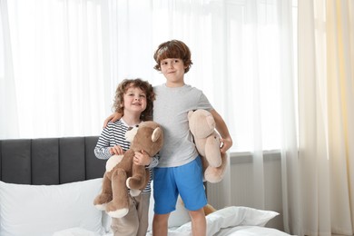 Photo of Cute little brothers with toys on bed at home