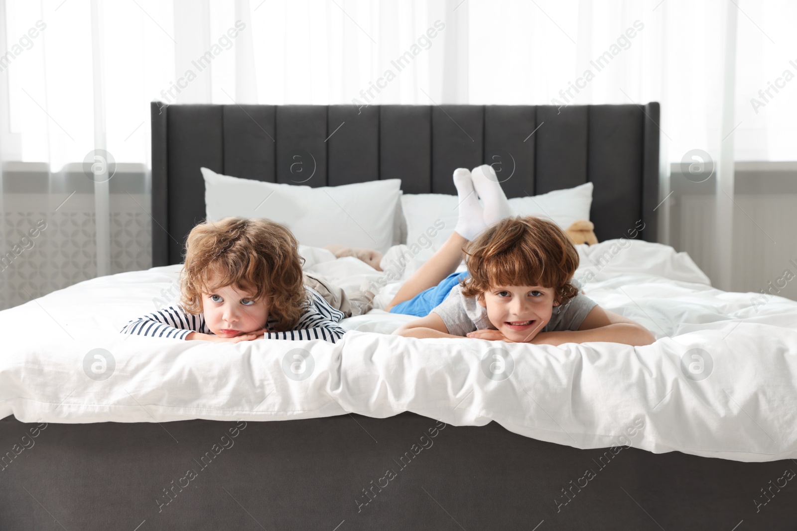 Cute little brothers laying on bed at home Photo of Cute little brothers laying on bed at home