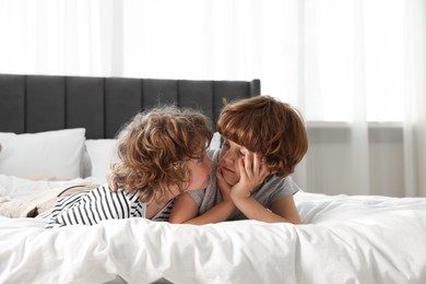 Photo of Cute little brothers laying on bed at home