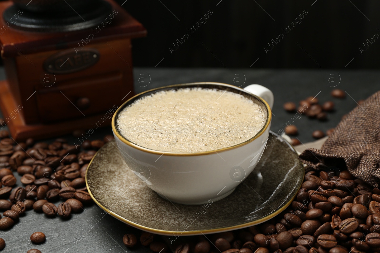 Aromatic coffee in cup, beans and grinder on black table, closeup Photo of Aromatic coffee in cup, beans and grinder on black table, closeup