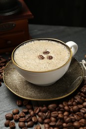 Photo of Aromatic coffee in cup, beans and grinder on black table, closeup