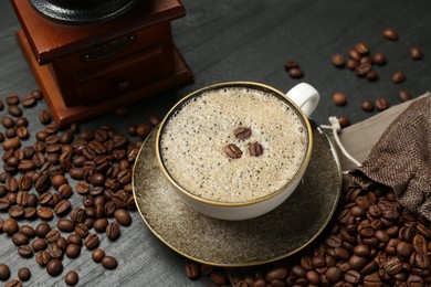 Photo of Aromatic coffee in cup, beans and grinder on black table, above view