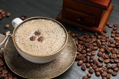 Photo of Aromatic coffee in cup, beans and grinder on black table, closeup