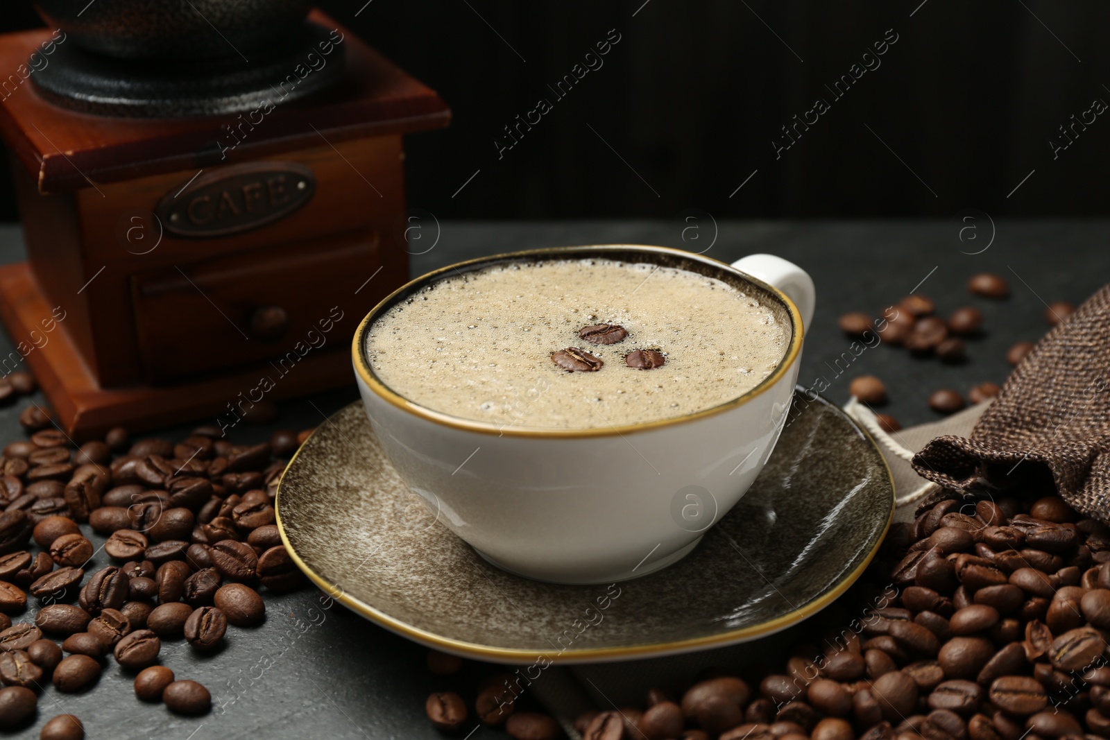 Aromatic coffee in cup, beans and grinder on black table, closeup Photo of Aromatic coffee in cup, beans and grinder on black table, closeup