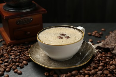Photo of Aromatic coffee in cup, beans and grinder on black table, closeup