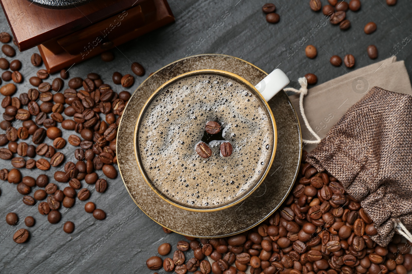 Aromatic coffee in cup, beans and grinder on black table, flat lay Photo of Aromatic coffee in cup, beans and grinder on black table, flat lay