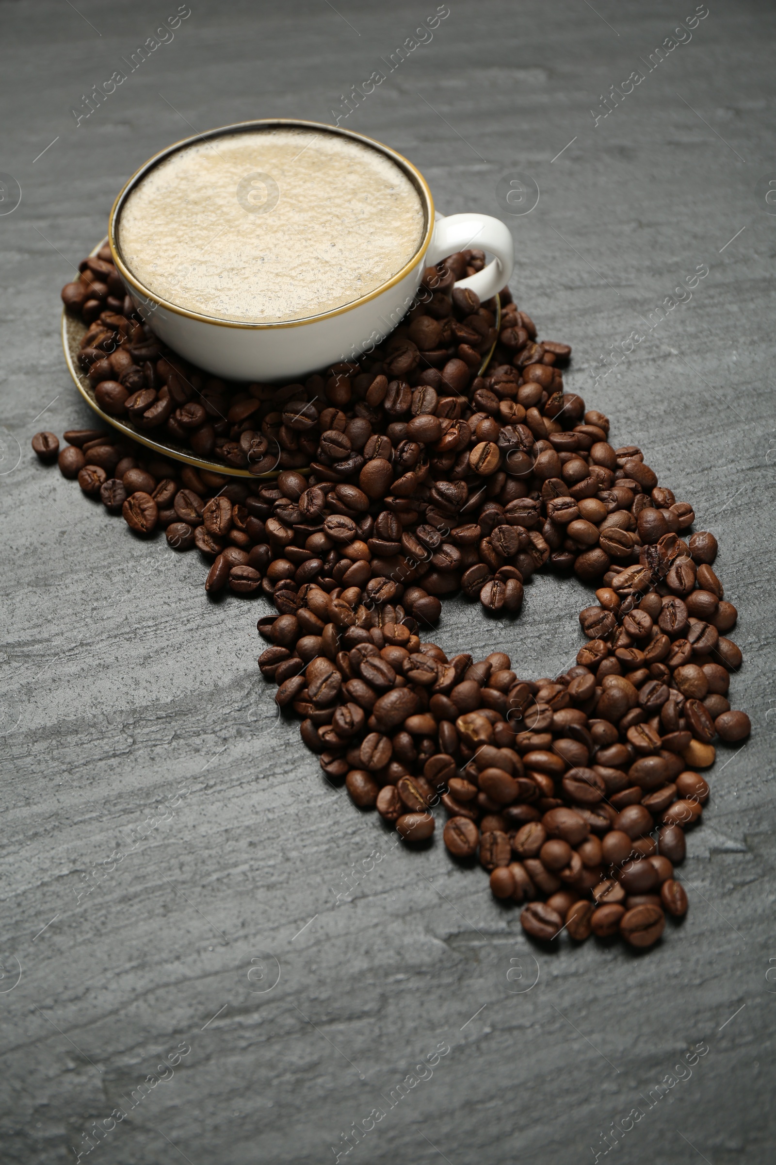 Aromatic coffee in cup and heart shaped of beans on black table Photo of Aromatic coffee in cup and heart shaped of beans on black table